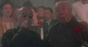 Movie still from “Shanghai Triad” (1995), directed by Yimou Zhang – Two older men are standing in front of a group of people; Close Up shot, Low angle