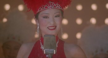 Movie still from “Shanghai Triad” (1995), directed by Yimou Zhang – A woman in a red dress is singing into a microphone; Close Up shot, Low angle