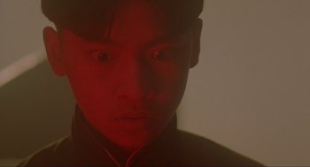 Movie still from “Shanghai Triad” (1995), directed by Yimou Zhang – A young man with a red shirt is looking at the camera; Close Up shot, Low angle