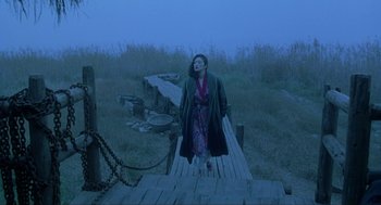 Movie still from “Shanghai Triad” (1995), directed by Yimou Zhang – A woman standing on top of a wooden dock; Wide shot, High angle