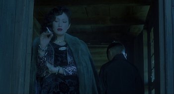 Movie still from “Shanghai Triad” (1995), directed by Yimou Zhang – A woman in a black dress and a man in a black jacket; Medium shot, Low angle
