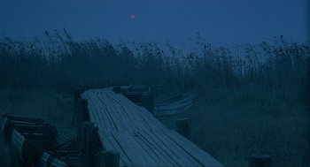 Movie still from “Shanghai Triad” (1995), directed by Yimou Zhang – A wooden dock with a boat on it at night; Extreme Wide shot, High angle