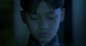 Movie still from “Shanghai Triad” (1995), directed by Yimou Zhang – A young boy with his eyes closed and his head tilted to the side; Close Up shot, High angle