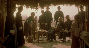 Movie still from “Shanghai Triad” (1995), directed by Yimou Zhang – A group of people sitting on a porch; Wide shot, Over the shoulder angle