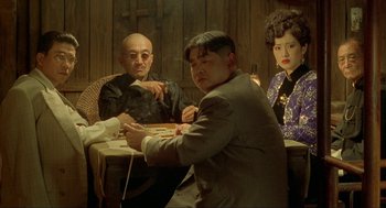 Movie still from “Shanghai Triad” (1995), directed by Yimou Zhang – A group of people sitting around a table; Medium shot, Low angle