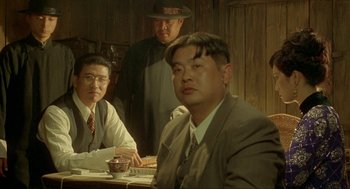 Movie still from “Shanghai Triad” (1995), directed by Yimou Zhang – A group of men sitting around a table; Medium shot, Over the shoulder angle