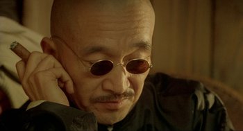 Movie still from “Shanghai Triad” (1995), directed by Yimou Zhang – An older man with a bald head wearing sunglasses; Close Up shot, High angle