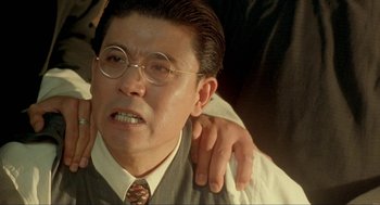 Movie still from “Shanghai Triad” (1995), directed by Yimou Zhang – An older man with glasses is holding another older man's shoulder; Close Up shot, Low angle