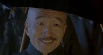 Movie still from “Shanghai Triad” (1995), directed by Yimou Zhang – An older man with a bald head wearing a black hat; Close Up shot, Low angle