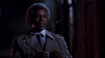 Movie still from “Sharky's Machine” (1981), directed by Burt Reynolds – A man in a trench coat and a tie; Close Up shot, Low angle