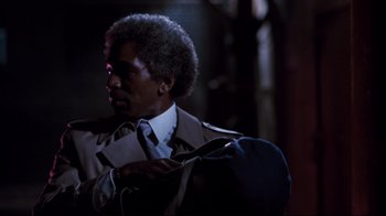 Movie still from “Sharky's Machine” (1981), directed by Burt Reynolds – A man in a suit and tie holding a bag; Close Up shot, Over the shoulder angle