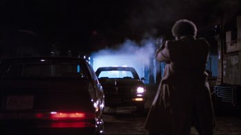 Movie still from “Sharky's Machine” (1981), directed by Burt Reynolds – A person taking a picture of a car on a street at night; Wide shot, Low angle