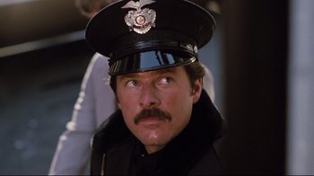 Movie still from “Sharky's Machine” (1981), directed by Burt Reynolds – A man in a police uniform with a serious look on his face; Close Up shot, Low angle