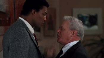 Movie still from “Sharky's Machine” (1981), directed by Burt Reynolds – Two men in business suits talking to each other; Medium shot, Over the shoulder angle