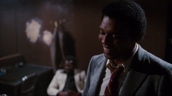 Movie still from “Sharky's Machine” (1981), directed by Burt Reynolds – A man wearing a suit and tie with a cigarette in his mouth; Close Up shot, Over the shoulder angle