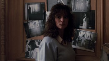 Movie still from “Sharky's Machine” (1981), directed by Burt Reynolds – A woman standing in front of a bunch of pictures; Medium shot, Over the shoulder angle