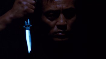 Movie still from “Sharky's Machine” (1981), directed by Burt Reynolds – A person holding a knife in a dark room; Close Up shot, Low angle