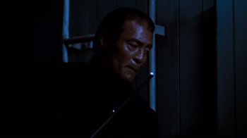 Movie still from “Sharky's Machine” (1981), directed by Burt Reynolds – A man in a black shirt holding a stick; Close Up shot, Low angle