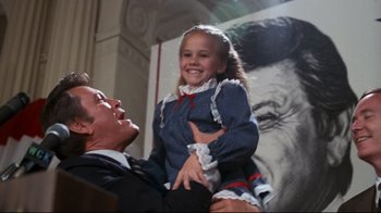 Movie still from “Sharky's Machine” (1981), directed by Burt Reynolds – A man holding a little girl on his shoulders; Medium shot, Low angle