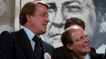 Movie still from “Sharky's Machine” (1981), directed by Burt Reynolds – A man in a suit and tie next to another man in a suit and tie; Medium shot, Low angle