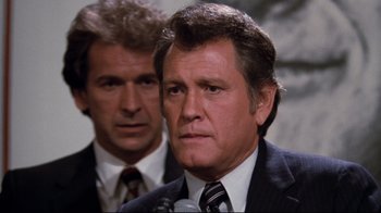 Movie still from “Sharky's Machine” (1981), directed by Burt Reynolds – A man in a suit and tie next to another man in a suit and tie; Close Up shot, Over the shoulder angle