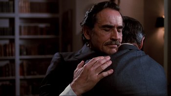 Movie still from “Sharky's Machine” (1981), directed by Burt Reynolds – An older man hugging a younger man in a room; Medium shot, Over the shoulder angle