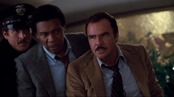 Movie still from “Sharky's Machine” (1981), directed by Burt Reynolds – Two men in suits and ties looking at the camera; Close Up shot, Low angle