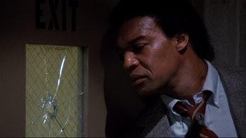 Movie still from “Sharky's Machine” (1981), directed by Burt Reynolds – A man in a suit and tie looking at a broken window; Close Up shot, Low angle