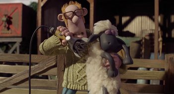 Movie still from “Shaun the Sheep Movie” (2015), directed by Mark Burton – A man holding a stuffed sheep with a hammer; Medium shot, High angle