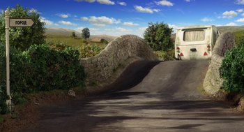 Movie still from “Shaun the Sheep Movie” (2015), directed by Mark Burton – A car driving down a road next to a stone wall; Wide shot, High angle