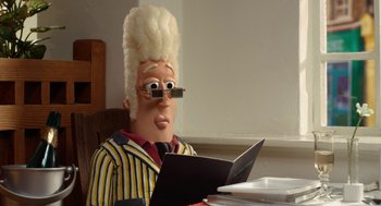 Movie still from “Shaun the Sheep Movie” (2015), directed by Mark Burton – A man with a wig and glasses is sitting at a table with a computer; Close Up shot, Low angle