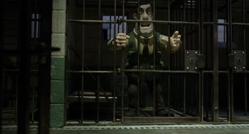 Movie still from “Shaun the Sheep Movie” (2015), directed by Mark Burton – A statue of a man behind bars in a jail cell; Wide shot, High angle