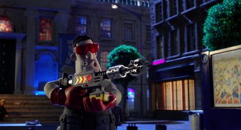 Movie still from “Shaun the Sheep Movie” (2015), directed by Mark Burton – A man holding a toy gun in front of a building; Wide shot, Over the shoulder angle