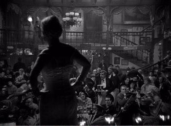 A woman standing in front of a crowd of people holding musical instruments