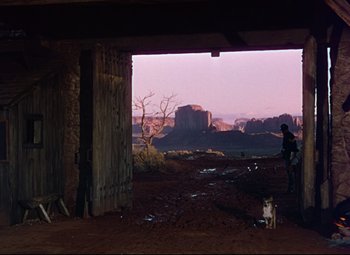 Movie still from “She Wore a Yellow Ribbon” (1949), directed by John Ford – An open barn door with a view of a desert landscape; Extreme Wide shot, Over the shoulder angle