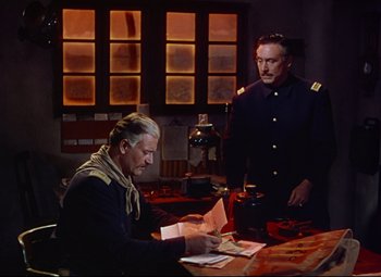 Movie still from “She Wore a Yellow Ribbon” (1949), directed by John Ford – Two men are sitting at a table and one is looking at papers; Medium shot, High angle