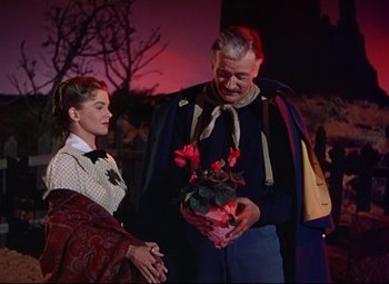 Movie still from “She Wore a Yellow Ribbon” (1949), directed by John Ford – An older man and woman holding a bouquet of flowers; Medium shot, Over the shoulder angle