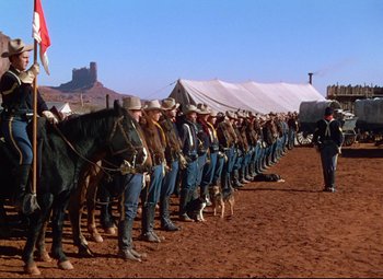 Movie still from “She Wore a Yellow Ribbon” (1949), directed by John Ford – A group of men on horses standing in front of a tent; Wide shot, Low angle