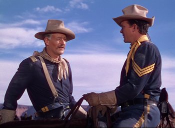 Movie still from “She Wore a Yellow Ribbon” (1949), directed by John Ford – Two men in cowboy hats talking to each other; Medium shot, Low angle