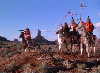 Movie still from “She Wore a Yellow Ribbon” (1949), directed by John Ford – A group of people riding horses on top of a dirt hill; Wide shot, Low angle