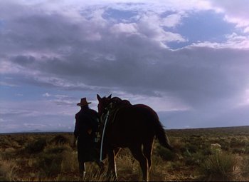 Movie still from “She Wore a Yellow Ribbon” (1949), directed by John Ford – A man in a cowboy hat is leading a horse; Extreme Wide shot, Low angle