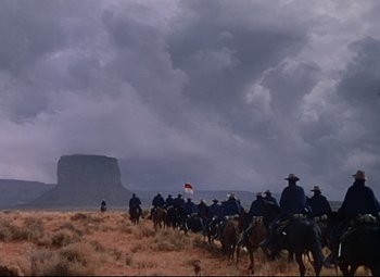 Movie still from “She Wore a Yellow Ribbon” (1949), directed by John Ford – A group of people riding horses in a field; Extreme Wide shot, Low angle