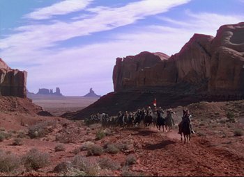 Movie still from “She Wore a Yellow Ribbon” (1949), directed by John Ford – A group of people on horseback traveling through the desert; Extreme Wide shot, High angle