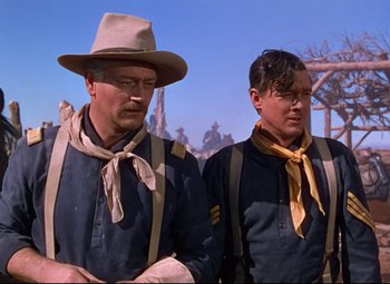 Movie still from “She Wore a Yellow Ribbon” (1949), directed by John Ford – A couple of men standing next to each other on top of a field; Medium shot, Low angle