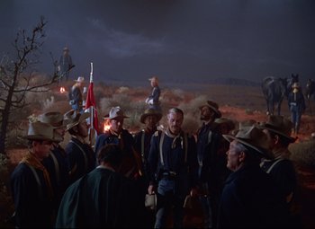 Movie still from “She Wore a Yellow Ribbon” (1949), directed by John Ford – A group of men in uniform standing next to each other on a field; Wide shot, Low angle