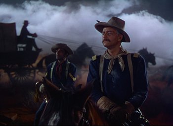 Movie still from “She Wore a Yellow Ribbon” (1949), directed by John Ford – Two men on horses in a dark setting; Wide shot, Low angle