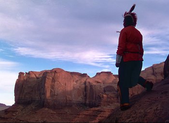 Movie still from “She Wore a Yellow Ribbon” (1949), directed by John Ford – A man in a red jacket is walking on a mountain; Wide shot, Low angle