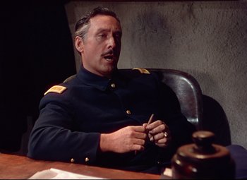 Movie still from “She Wore a Yellow Ribbon” (1949), directed by John Ford – A man in a uniform sitting at a table; Medium shot, High angle