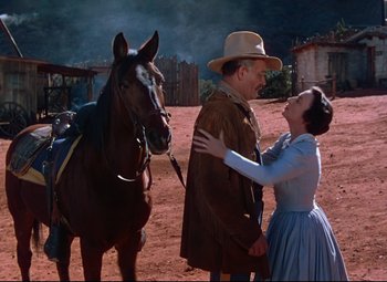 Movie still from “She Wore a Yellow Ribbon” (1949), directed by John Ford – A man and a woman standing next to a brown horse; Medium shot, Low angle
