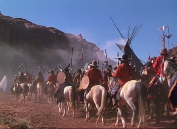 Movie still from “She Wore a Yellow Ribbon” (1949), directed by John Ford – A group of people on horseback riding on a dirt road; Wide shot, High angle
